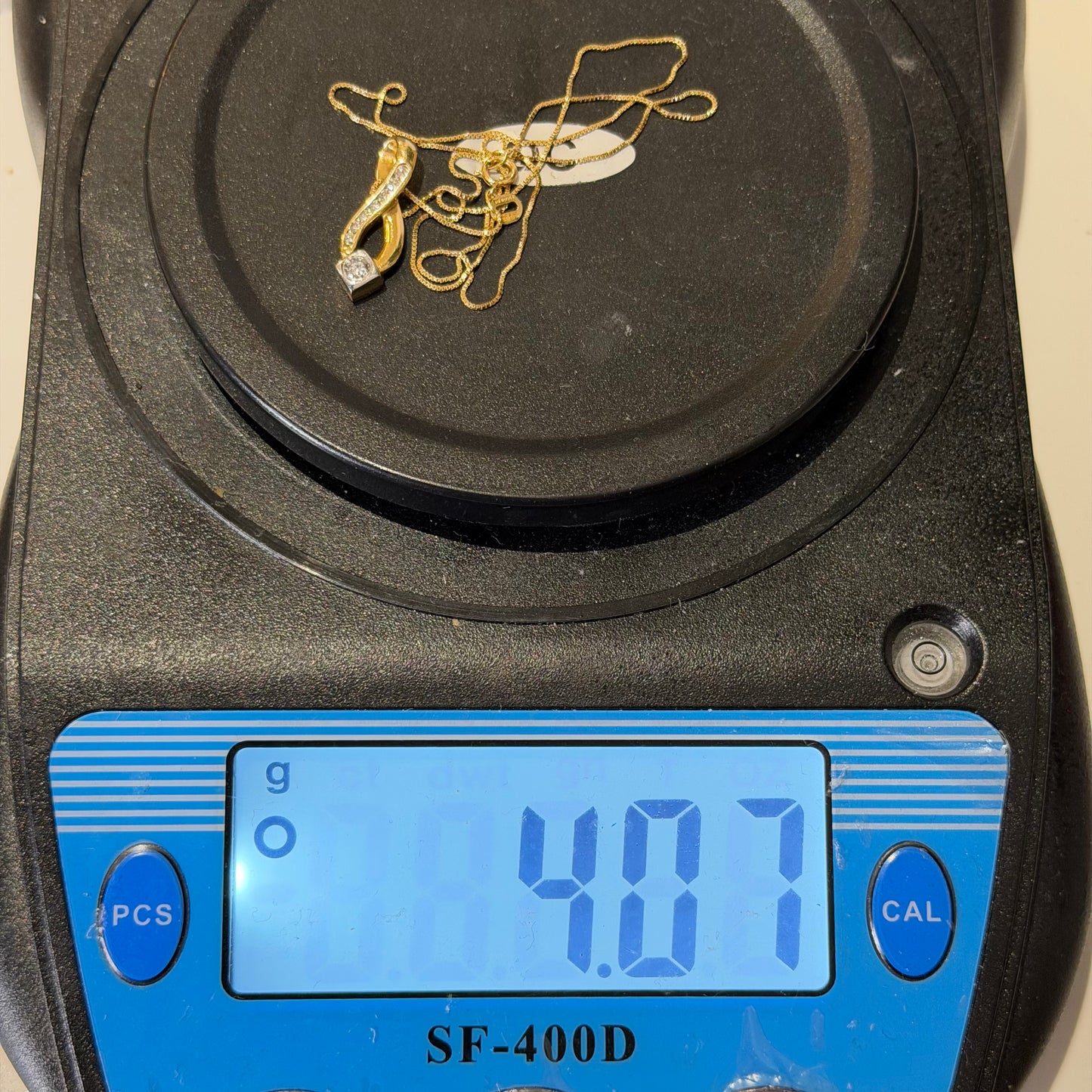 18ct Gold 0.4ct Diamond Pendant on 18in Box Chain, Hallmarked 4.1g, displayed on scale reading 4.07g.
